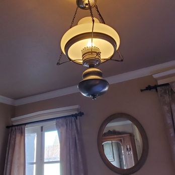 Murphys Historic Hotel - Lighting - A vintage-style ceiling lamp with a chain is suspended from the ceiling in a room with beige walls and curtains. - Hotels Near Me - Murphys, California