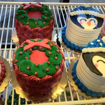 Smallcakes A Cupcakery - Assorted cakes with Christmas motifs, including wreaths and snowmen, decorated with colorful icing and fondant details. - Bakeries Near Me - Albuquerque, New Mexico