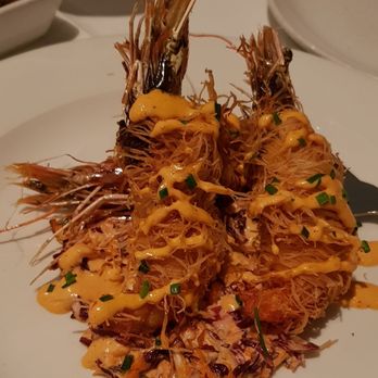 Prezza - Fried shrimp with a crispy exterior, drizzled with a creamy orange sauce and garnished with chopped chives, served on a white plate. - Italian Near Me - Boston, Massachusetts