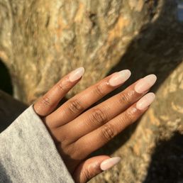 OPI  "Bubble Bath" polish with shimmer on almond tips by Jade! - A hand with neatly manicured, light-colored nails is shown outdoors, with a tree trunk in the background.