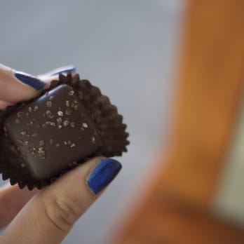 Purdys Chocolatier - a hand holding a piece of chocolate - Ice Cream & Frozen Yogurt Near Me - Vancouver, British Columbia