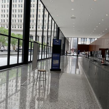 USPS - A spacious USPS lobby features large glass windows, a postal service sign, and a polished granite floor, with a few outside pedestrians visible. - Post Offices Near Me - Chicago, Illinois