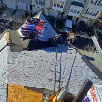 Roofer 911 - Work in progress - Two workers are installing roofing materials and insulation on a residential building's roof, with tools and materials visible. - Roofing Near Me