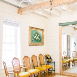 Cleo Bridal - Fitting room area with yellow chairs and a large mirror.