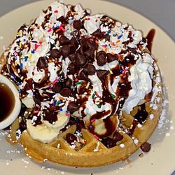 Waffle Shop - Chocolate chip pecan waffle topped with powdered sugar, bananas, whipped cream, chocolate sauce, and rainbow sprinkles.