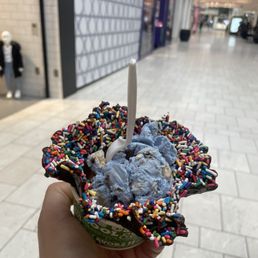 a hand holding an ice cream cone with sprinkles