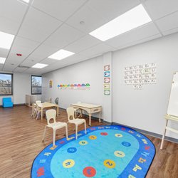 Merlin Day Academy - Classroom with brightly colored rug and whiteboard.