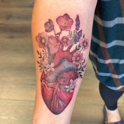 Sacred Nine Tattoo Studio - Realistic color anatomical heart and flowers on forearm.