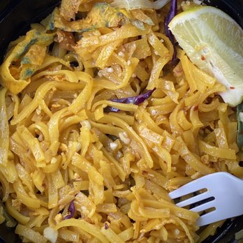 Thai Cafe - Showing the very yellow Pad Thai noodles (possibly curry noodles altered to make Pad Thai). - A serving of Pad Thai noodles with yellow curry-like coloring, garnished with lemon, vegetables, and crispy toppings. - Thai Near Me - Ottawa, Illinois