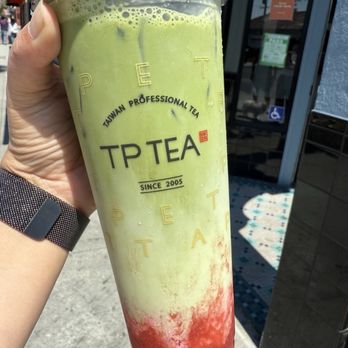 TP Tea - Strawberry matcha latte - A person holds a tall, layered matcha and strawberry tea from TP Tea in Millbrae, CA, outside a shop with a bright, modern interior. - Bubble Tea Near Me - Millbrae, California