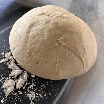 ooni - After 24 hrs cold proof- I am thinking I am making pizza tomorrow! - A round ball of pizza dough on a black surface, with some flour scattered around, in a kitchen setting. - Grilling Equipment Near Me - El Paso, Texas