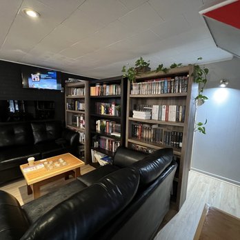Le Caf’ Micro-boulangerie - ws a living room with black leather couches and bookshelves - Bakeries Near Me - Saint-Jean-de-Dieu, Quebec Le Caf’ Micro-boulangerie - ws a living room with black leather couches and bookshelves - Bakeries Near Me - Saint-Jean-de-Dieu, Quebec