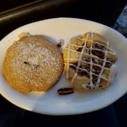 A white plate holds a cookie dusted with sugar and two decorated cookie bars topped with drizzle and chocolate pieces, from Cookie Time Bakery.