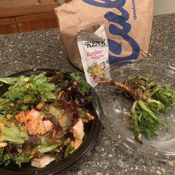 Culver's - A salad with mixed greens, chicken, and nuts is on a black plate, with a leftover shrimp and greens on a clear plastic container. A bag and raspberry vinaigrette packet are also visible. - Fast Food Near Me - Chicago, Illinois