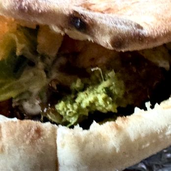 NYC Falafel - Falafel Pita Sandwich. Filled with fresh hot falafel,  crispy cool chopped salad, and layers of flavorful white sauce and spicy hot sauce - Halal Near Me - New York, New York
