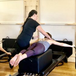 Studio M Pilates and Yoga - Keisha correcting form on a Clive today on the Reformer