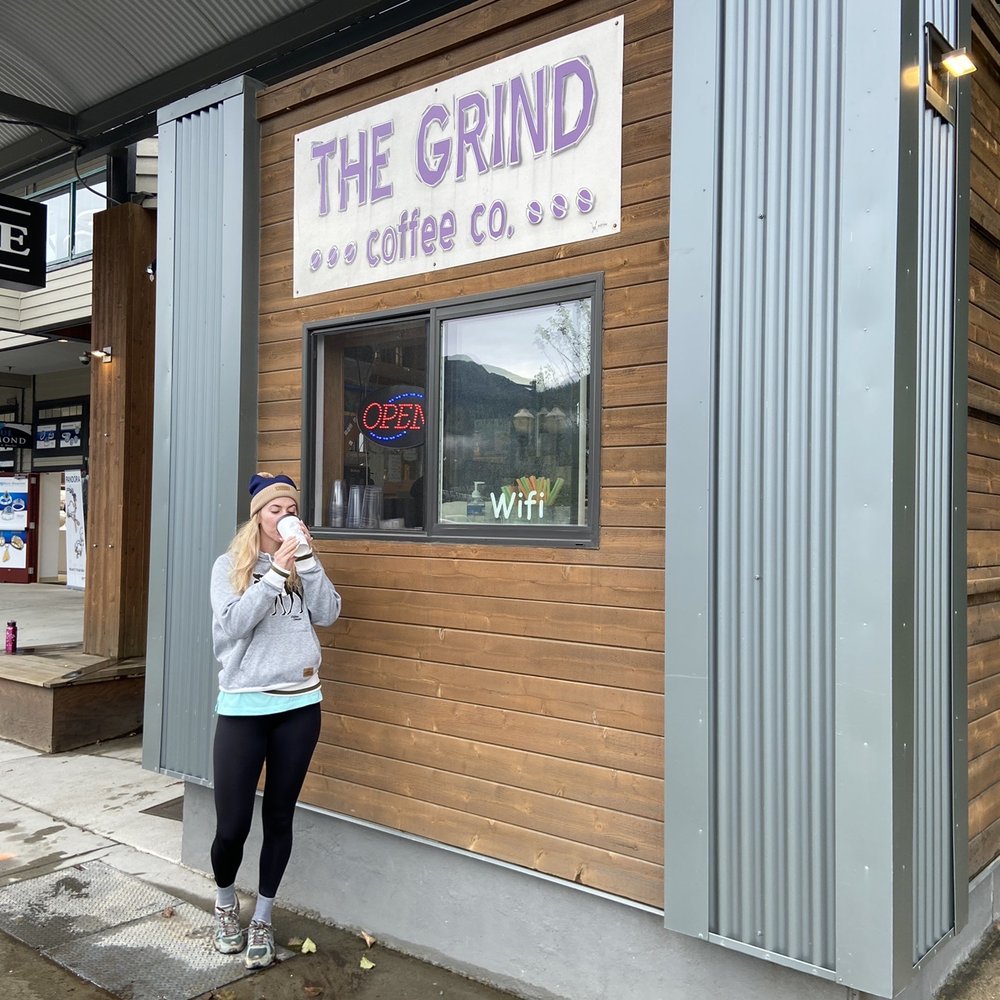 a woman standing in front of a coffee shop a woman standing in front of a coffee shop