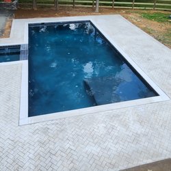 Alpha Le Concrete - Decorative concrete pool deck with a light stone pattern and clean border finish.
