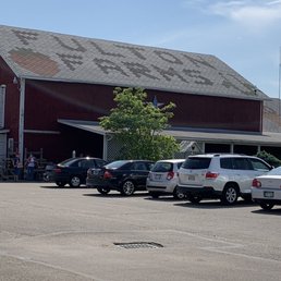 a parking lot with cars parked in front of a red barn a parking lot with cars parked in front of a red barn