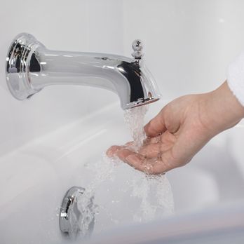 Bath Fitter - a person washing their hands under a faucet - General Contractors Near Me - Edmonton, Alberta