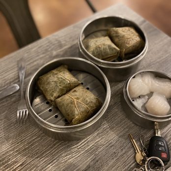IT DIMSUM - Three metal dim sum steamers contain leaf-wrapped rice cakes and shrimp dumplings, placed on a wooden table with utensils and keys nearby. - Dim Sum Near Me - Albuquerque, New Mexico