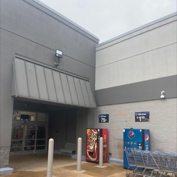 Walmart - Outside a retail store, two vending machines and shopping carts are visible near the entrance, with a bench and bollards nearby. - Department Stores Near Me - Burke, Virginia