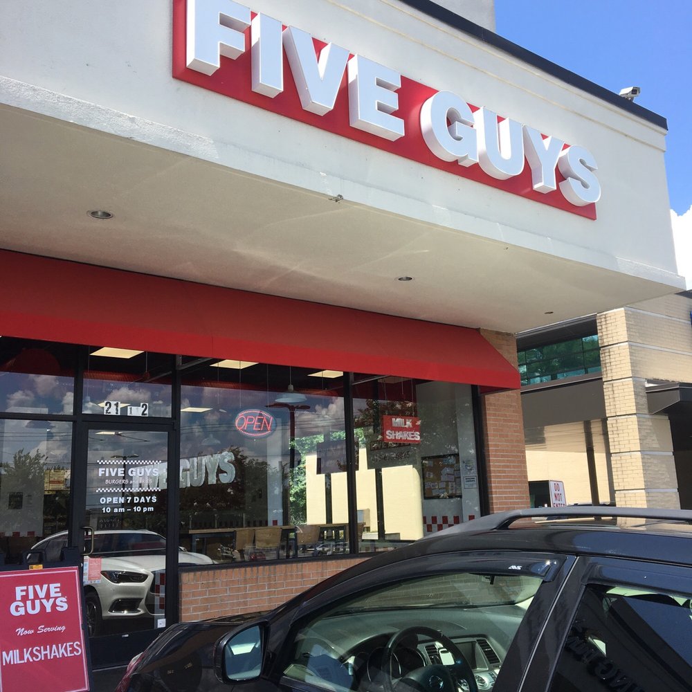 a car parked in front of a five guys restaurant
