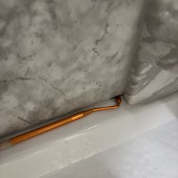 Bath Center - Tooth explorer showing depth of missing caulking