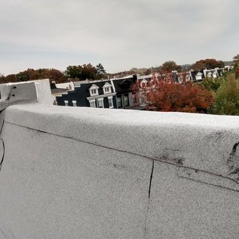 United Roofing - Above dormers which snow was infiltrating inside the drywall in front room guest suite causing  huge spotting - The image depicts a rooftop with snow infiltration problems, leading to damage on the drywall inside a room. The rooftop appears to have cracks and areas where snow has entered, affecting the interior drywall. The background shows a neighborhood with trees displaying fall colors and residential buildings, indicating an urban setting. - Roofing Near Me - Washington, DC, District of Columbia