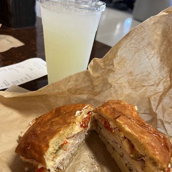 Wildflower - A sandwich with a golden-brown crust and a cold lemon drink in a clear cup are on a table at an airport restaurant. - New American Near Me - Phoenix, Arizona