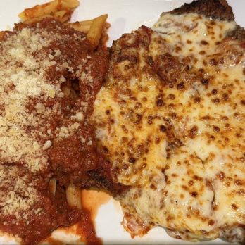 Brickhouse Cafe - Chicken Parmigiana with penne - The image shows a plate with a serving of chicken parmesan, topped with melted cheese and browned spots, alongside a portion of spaghetti pasta covered in tomato sauce and sprinkled with grated cheese. The dish appears to be served on a white plate, highlighting the Italian cuisine elements. - Italian Near Me - Dedham, Massachusetts
