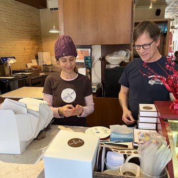 The Chocolate Room - Owners Naomi and John package decadent chocolates to be sent out for an order. - Desserts Near Me - Brooklyn, New York The Chocolate Room - Owners Naomi and John package decadent chocolates to be sent out for an order. - Desserts Near Me - Brooklyn, New York