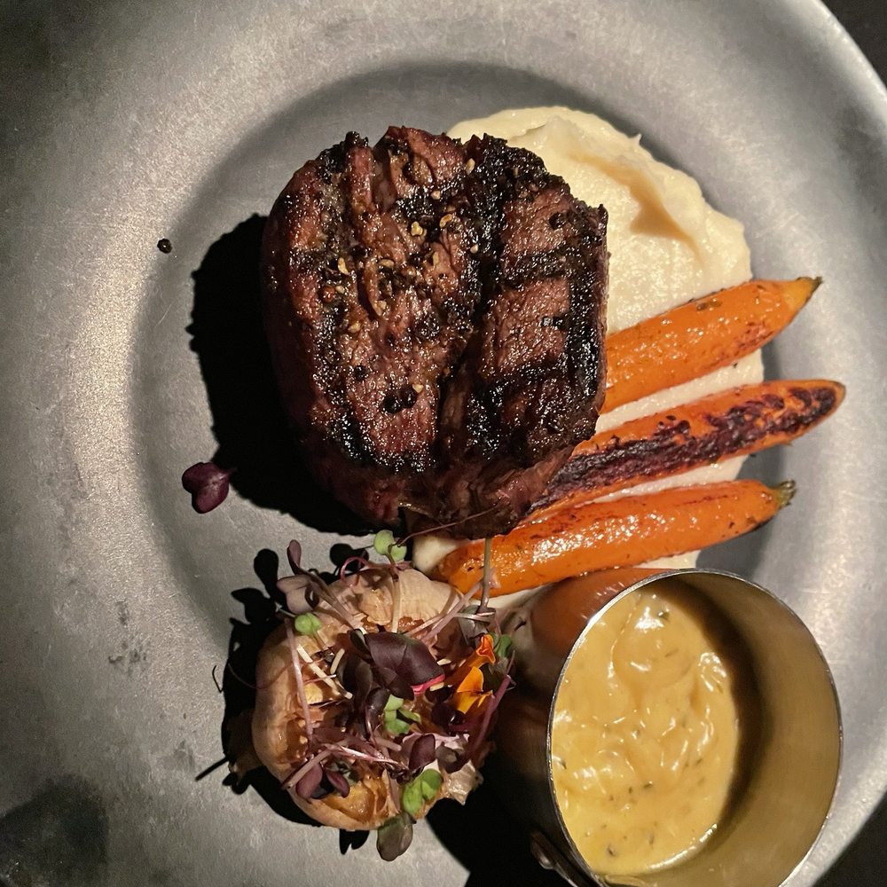 Filet minion with a whole grilled garlic head, mashed potatoes, carrots and Béarnaise sauce.
