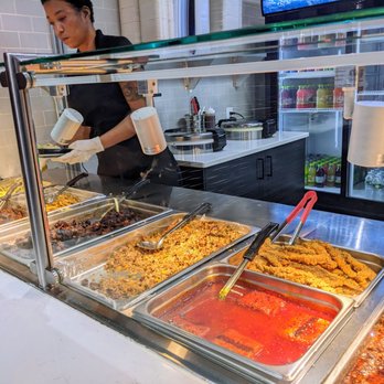 Jerk House - a woman preparing food in a buffet - Caribbean Near Me - New York, New York Jerk House - a woman preparing food in a buffet - Caribbean Near Me - New York, New York