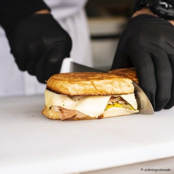 Bodega Cuban Kitchen - a person cutting a sandwich - Food Trucks Near Me - Denver, Colorado