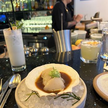 Quique Crudo - Aguachile de Negro (Maine live scallop Crudo). Left is Coco Mojo drink and right is Pineapple Margarita - Cocktail Bars Near Me - New York, New York Quique Crudo - Aguachile de Negro (Maine live scallop Crudo). Left is Coco Mojo drink and right is Pineapple Margarita - Cocktail Bars Near Me - New York, New York