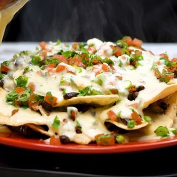 Los Caminos - a plate of nachos being drizzled with sauce - Mexican Near Me - Gibson City, Illinois Los Caminos - a plate of nachos being drizzled with sauce - Mexican Near Me - Gibson City, Illinois