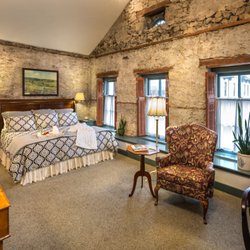 Washington House Inn - Historic room with stucco walls and luxurious bed, with four tall windows and nearby sitting and working areas