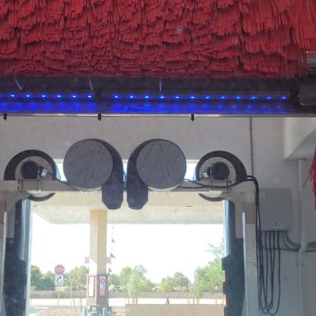 Circle K - Car Wash - A car wash station with red fabric decorations hanging from the ceiling and blue LED strip lighting, with a view of the outside area including stop signs and trees. - Convenience Stores Near Me - Glendale, Arizona