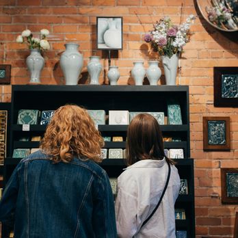 Pewabic - Two customers look at a wall of art tiles and vases. - Art Galleries Near Me - Detroit, Michigan Pewabic - Two customers look at a wall of art tiles and vases. - Art Galleries Near Me - Detroit, Michigan