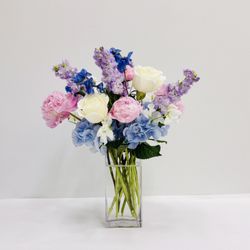 A romantic garden-style arrangement in dreamy shades of soft blue, blush pink, lavender, and crisp white.