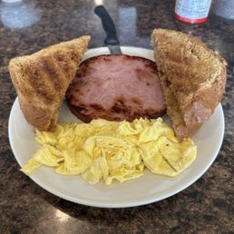 2 Eggs with Bacon - A breakfast plate featuring scrambled eggs, a slice of ham, and two toasted bread triangles, served on a white plate.