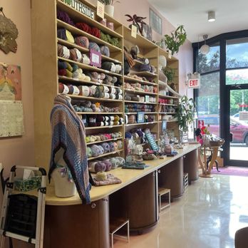 Miss Purl - Shops interior - Interior of a yarn store with shelves stocked with various yarns, knitting supplies, and potted plants, near the entrance. - Knitting Supplies Near Me - Chicago, Illinois