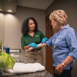 Home Instead - Home Instead Care Giver and their client in the bathoom, putting on a band aid