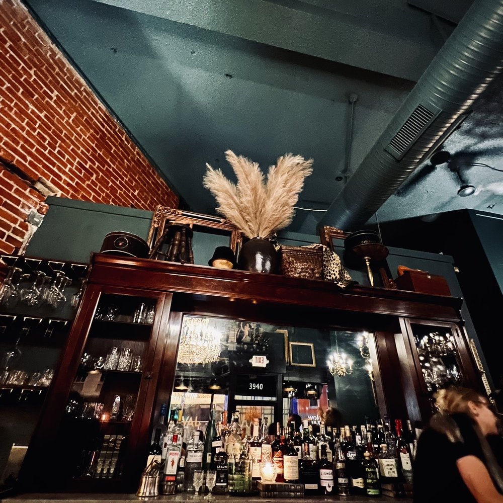 Cheval - a woman standing at a bar - Cocktail Bars Near Me - Kansas City, Missouri