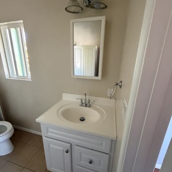 Happy Cleaning LA - A bathroom features a white vanity with a sink, a mirror above it, a small window with frosted glass, and a ceiling light fixture. - Home Cleaning Near Me - Glendale, California