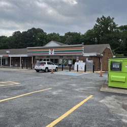 7-Eleven - Looking from the street,lime green dumpster, holiday Ice freezer, and propane tank cabinet to the right of the front entrance...