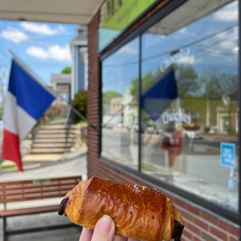 MA-France - a person holding a pastry in front of a store - French Near Me - Lexington, Massachusetts MA-France - a person holding a pastry in front of a store - French Near Me - Lexington, Massachusetts