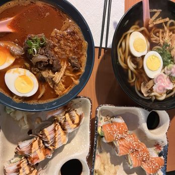 Sushibucks - Two bowls of ramen with boiled eggs, green onions, and meat, along with two sushi rolls drizzled with sauce, are displayed on a wooden table. - Japanese Near Me - Albuquerque, New Mexico