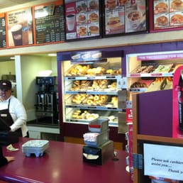  a woman behind a counter at a dunkin donuts shop